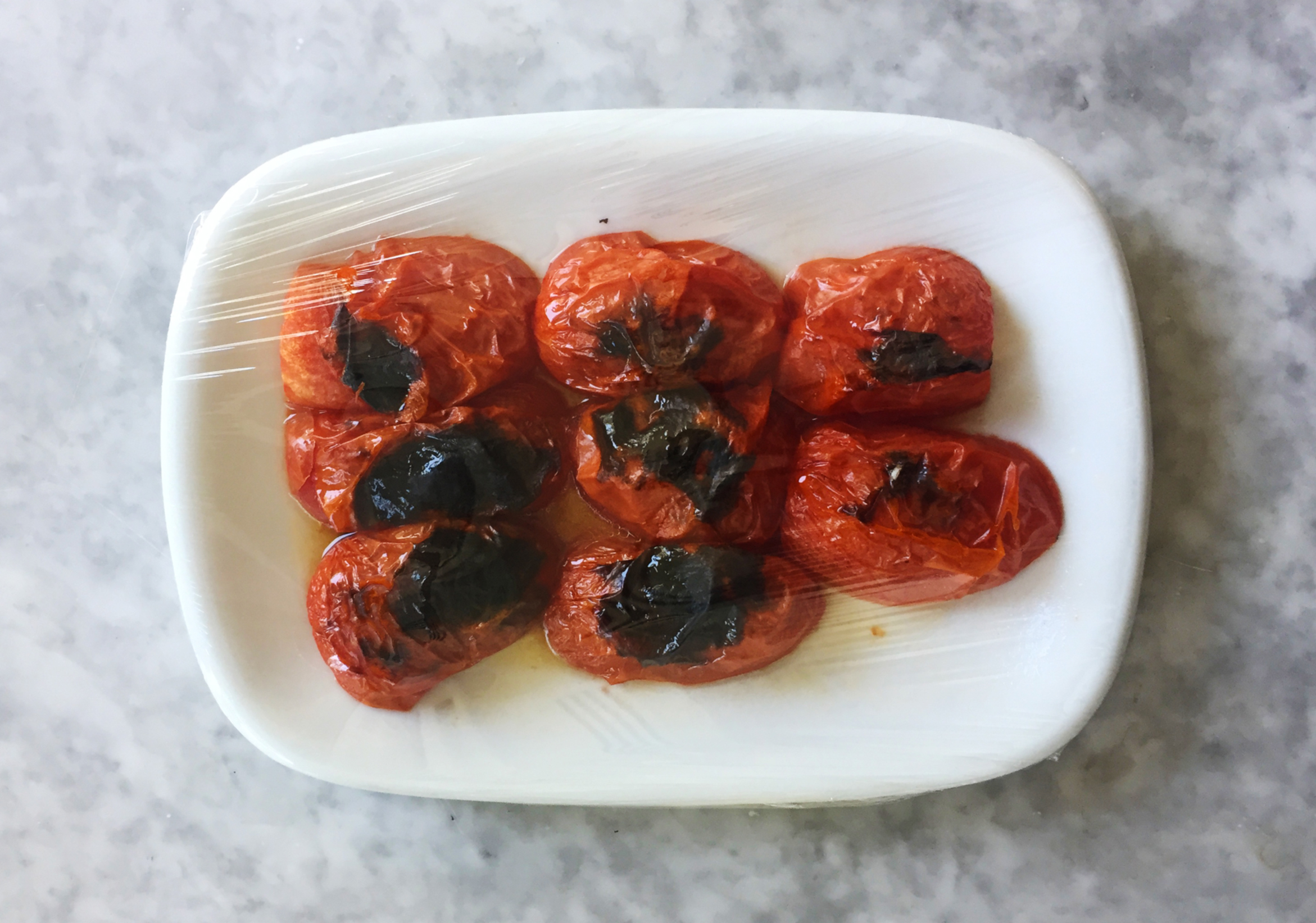 fire-roasted tomatoes Fire-roasted tomatoes on plate with plastic wrap.
