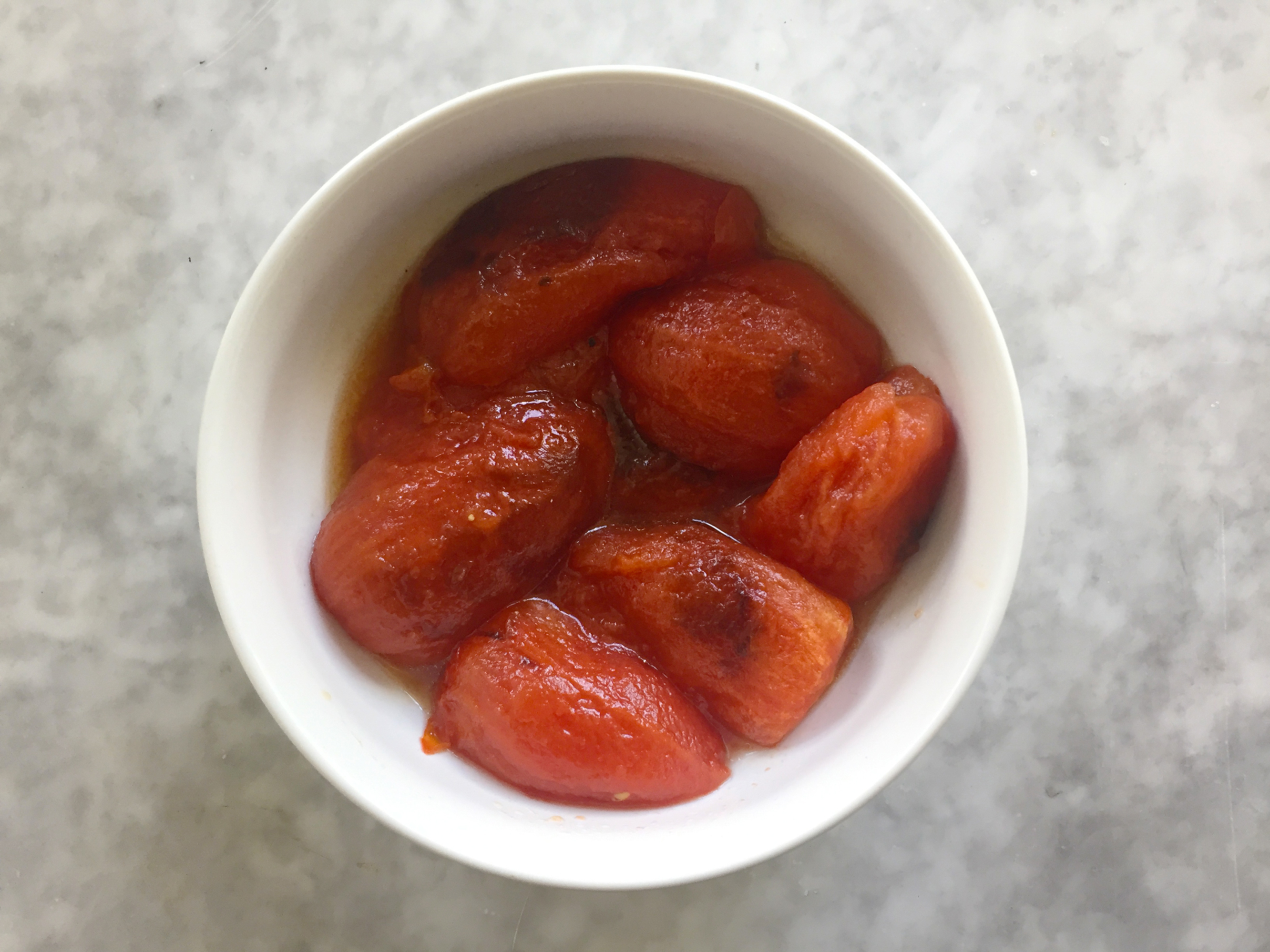 fire-roasted tomatoes in bowl Fire-roasted tomatoes without skins in bowls.
