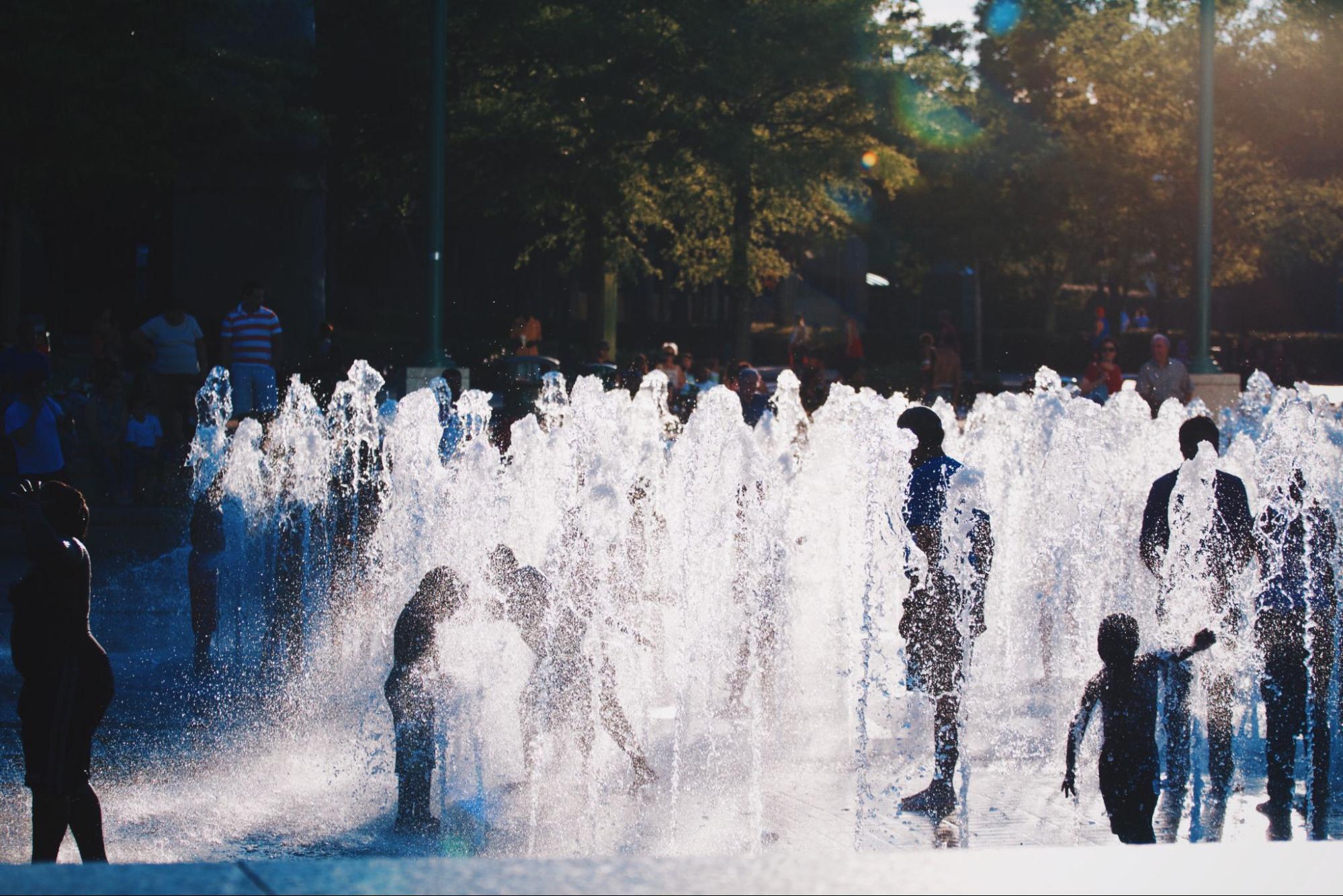 Family splashes around in fountain during the summer in Atlanta, Georgia.