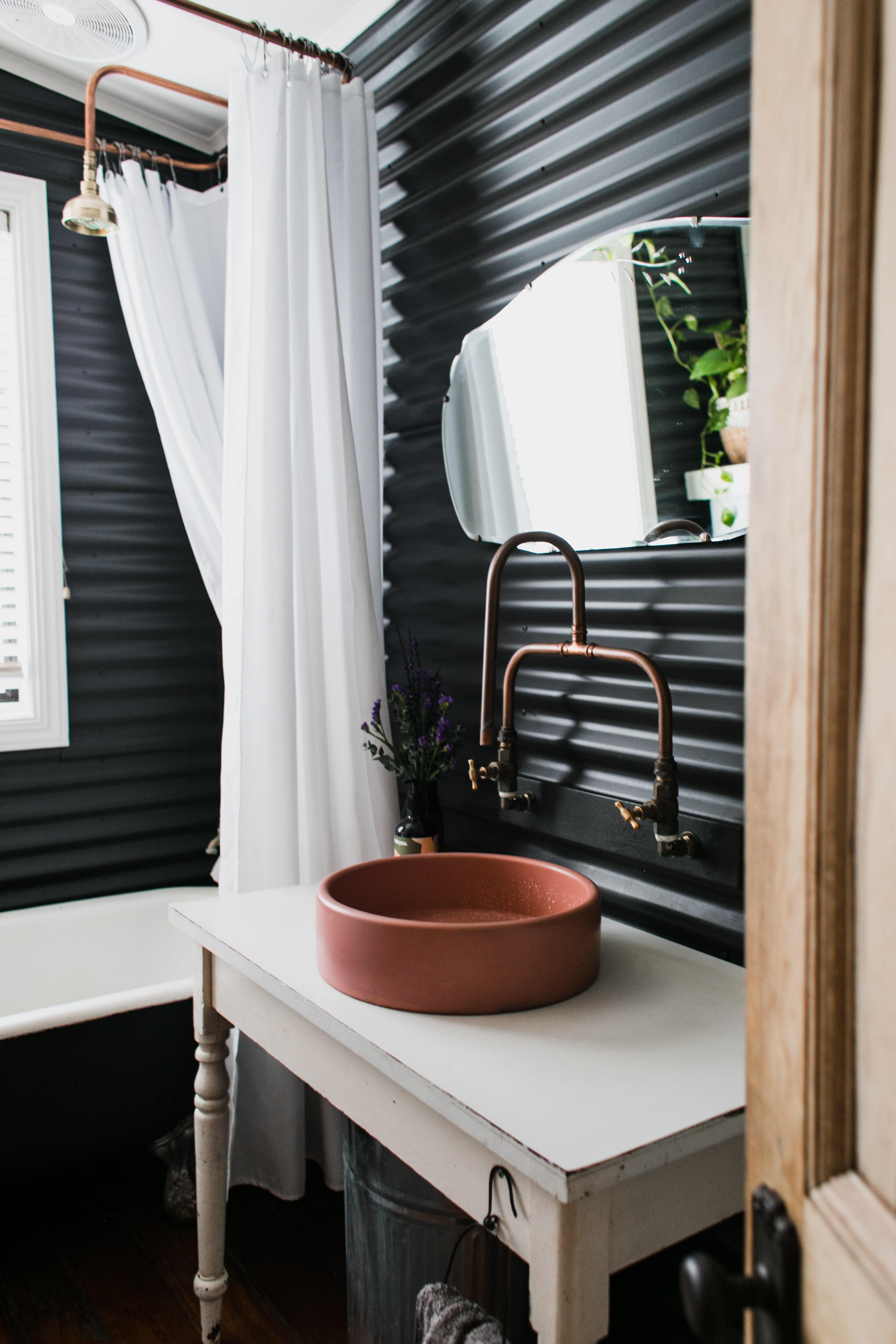 A well decorated bathroom has a bright copper sink.