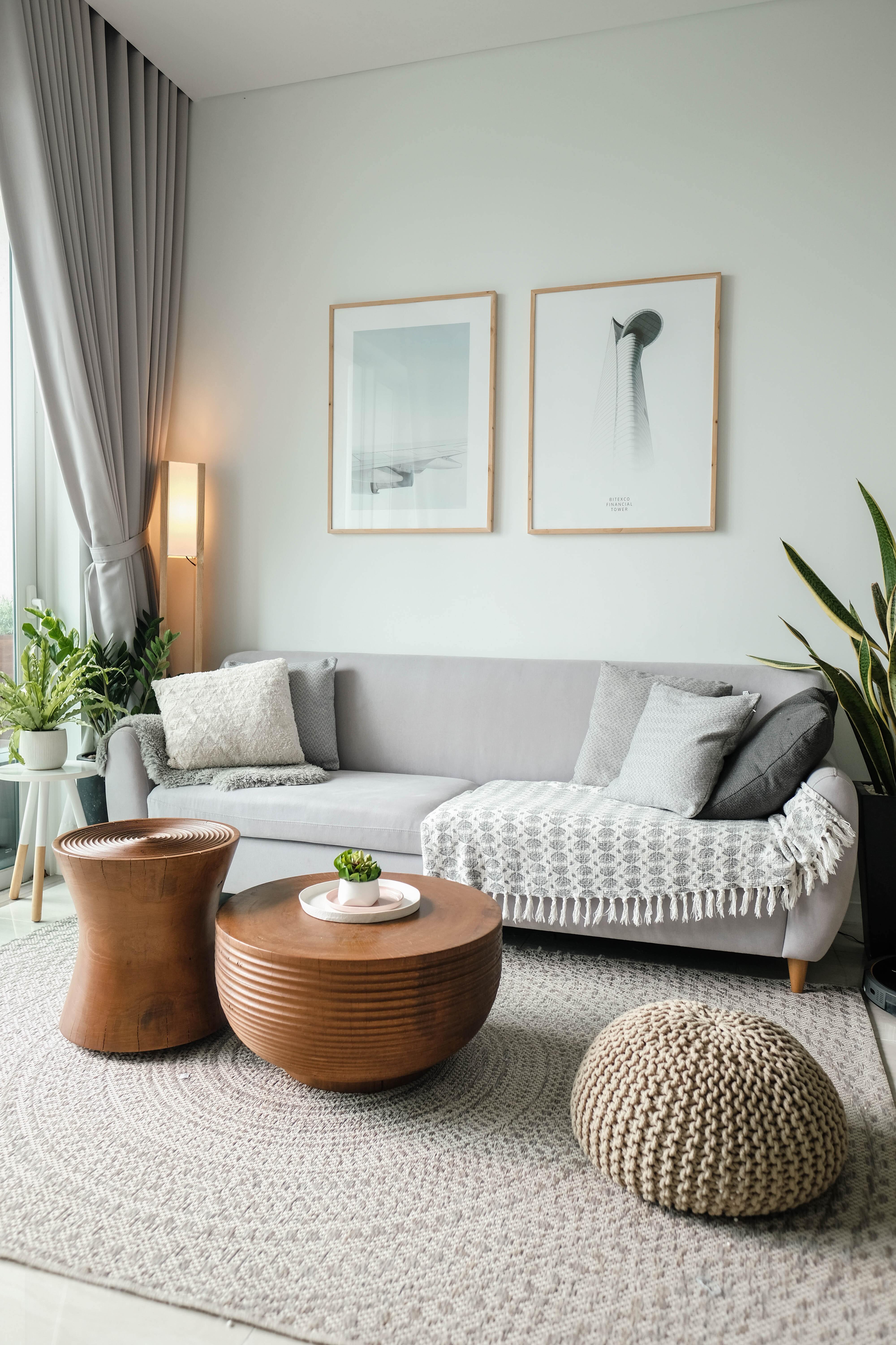 A living room with a couch, three ottomans, and several plants