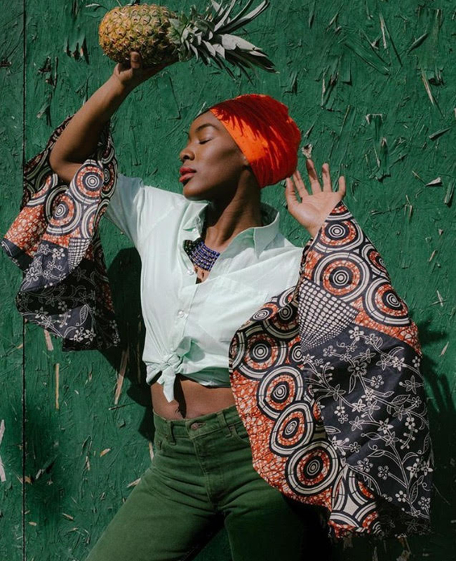 woman holding a pineapple African-American women wearing african prints and headwrap, holding a pineapple.