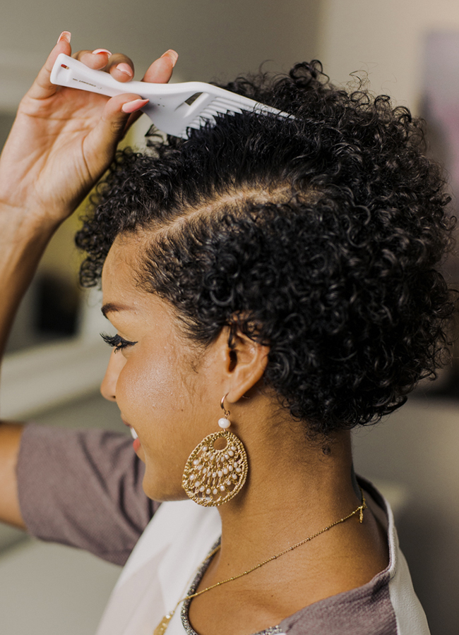 Woman with curly hair looking in the mirror picking hair